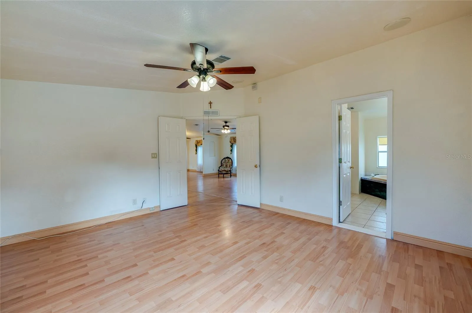 Spacious primary bedroom features a ceiling fan, double-door entry, and convenient direct access to the adjoining bathroom.
