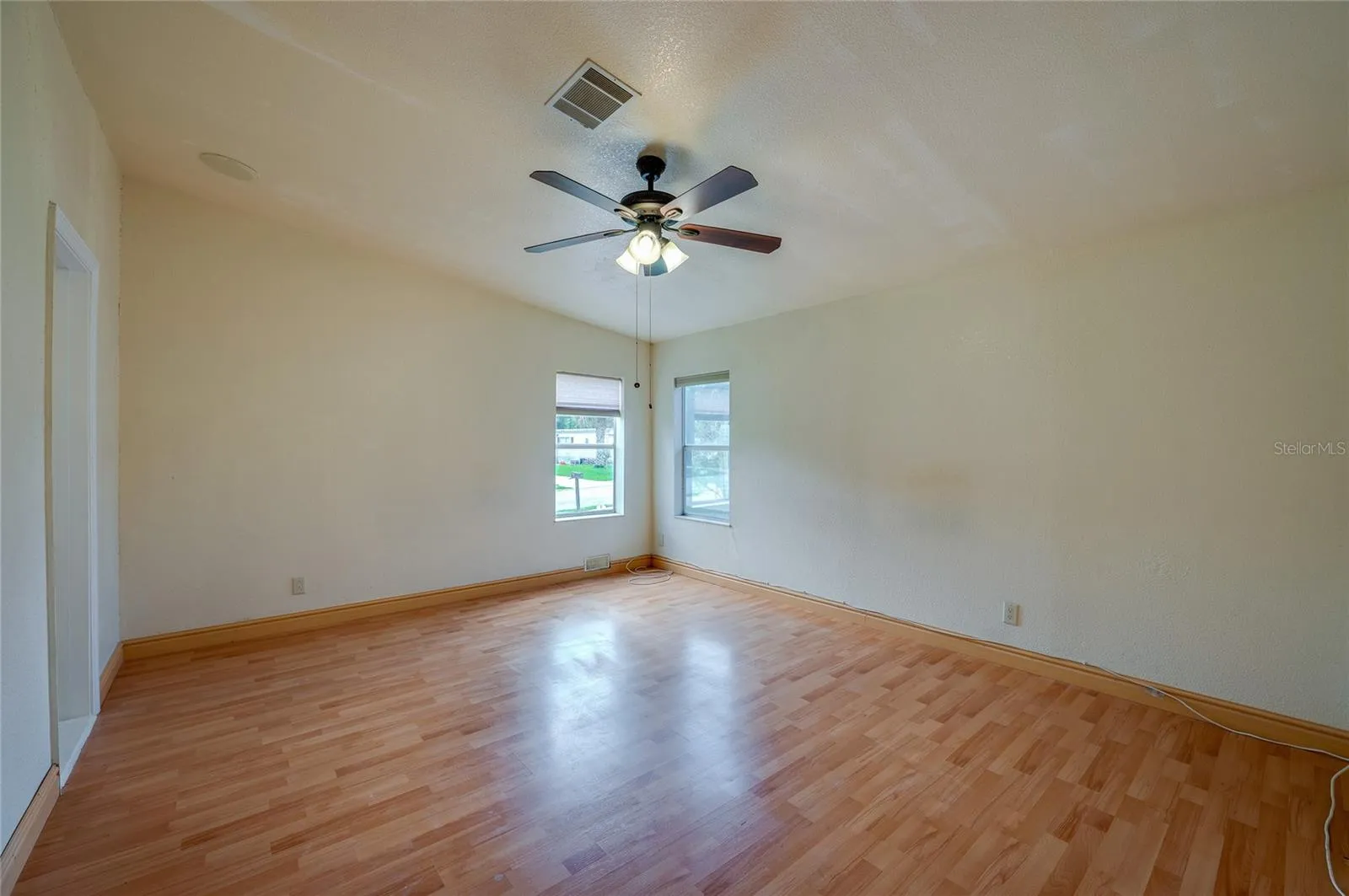 Generously sized primary bedroom with a ceiling fan, multiple windows for natural light, and ample wall space for a variety of furniture arrangements.