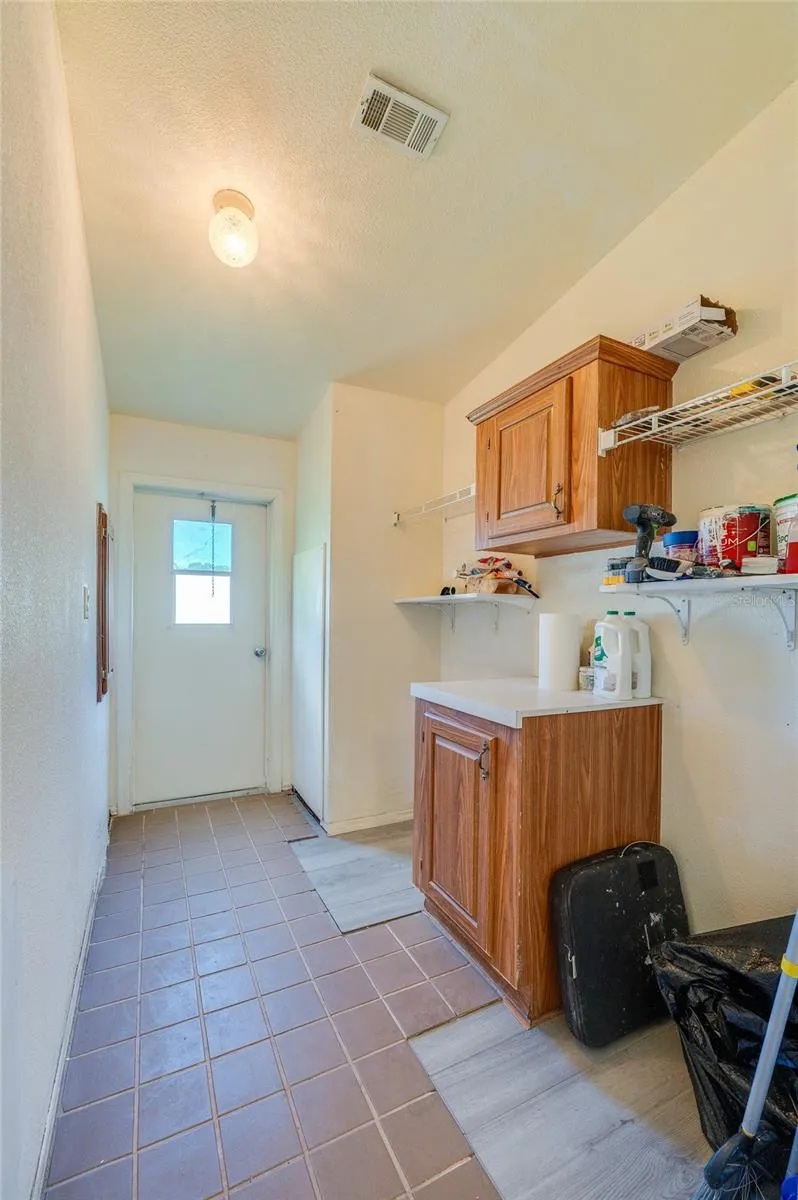 Functional utility space provides built-in cabinetry, open shelving, counter space, and direct exterior access for added convenience.