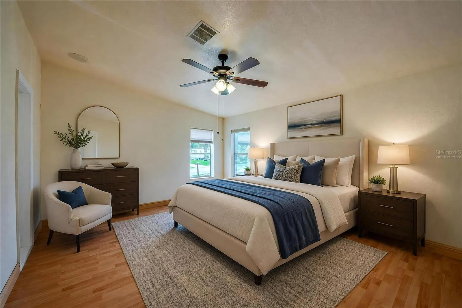 Virtually Staged...Generously sized primary bedroom with a ceiling fan, multiple windows for natural light, and ample wall space for a variety of furniture arrangements.