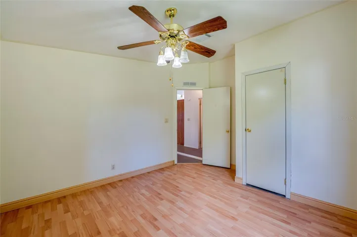 Alternate view highlights the room’s comfortable proportions, ceiling fan, and convenient closet storage.
