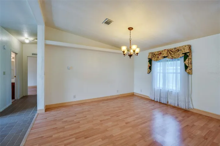 Defined dining space features a chandelier and a large window for natural light, with an open connection to the surrounding living areas.