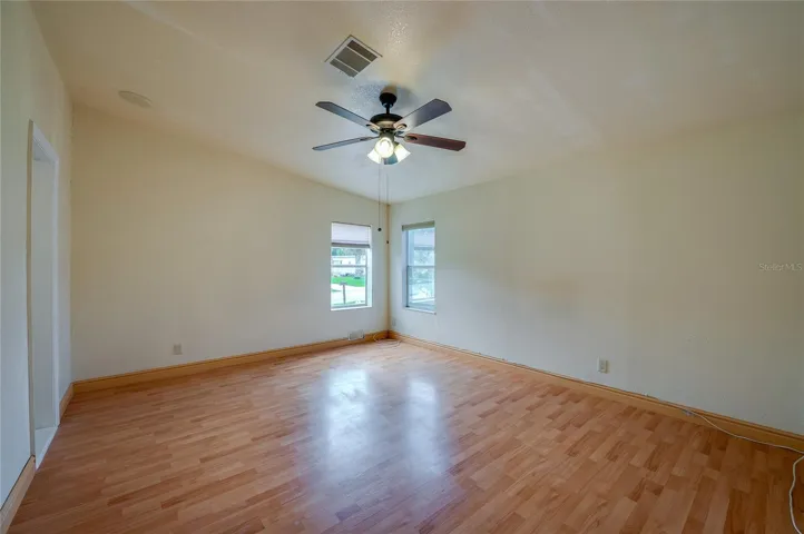 Generously sized primary bedroom with a ceiling fan, multiple windows for natural light, and ample wall space for a variety of furniture arrangements.
