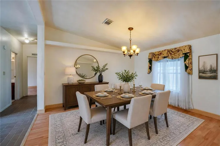 Virtually Staged...Defined dining space features a chandelier and a large window for natural light, with an open connection to the surrounding living areas.