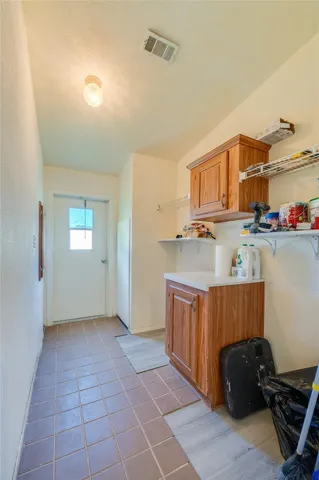 Functional utility space provides built-in cabinetry, open shelving, counter space, and direct exterior access for added convenience.