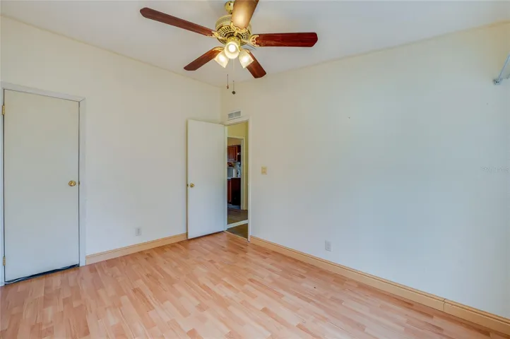 Alternate view of the bedroom showcases its comfortable proportions, ceiling fan, and convenient storage.