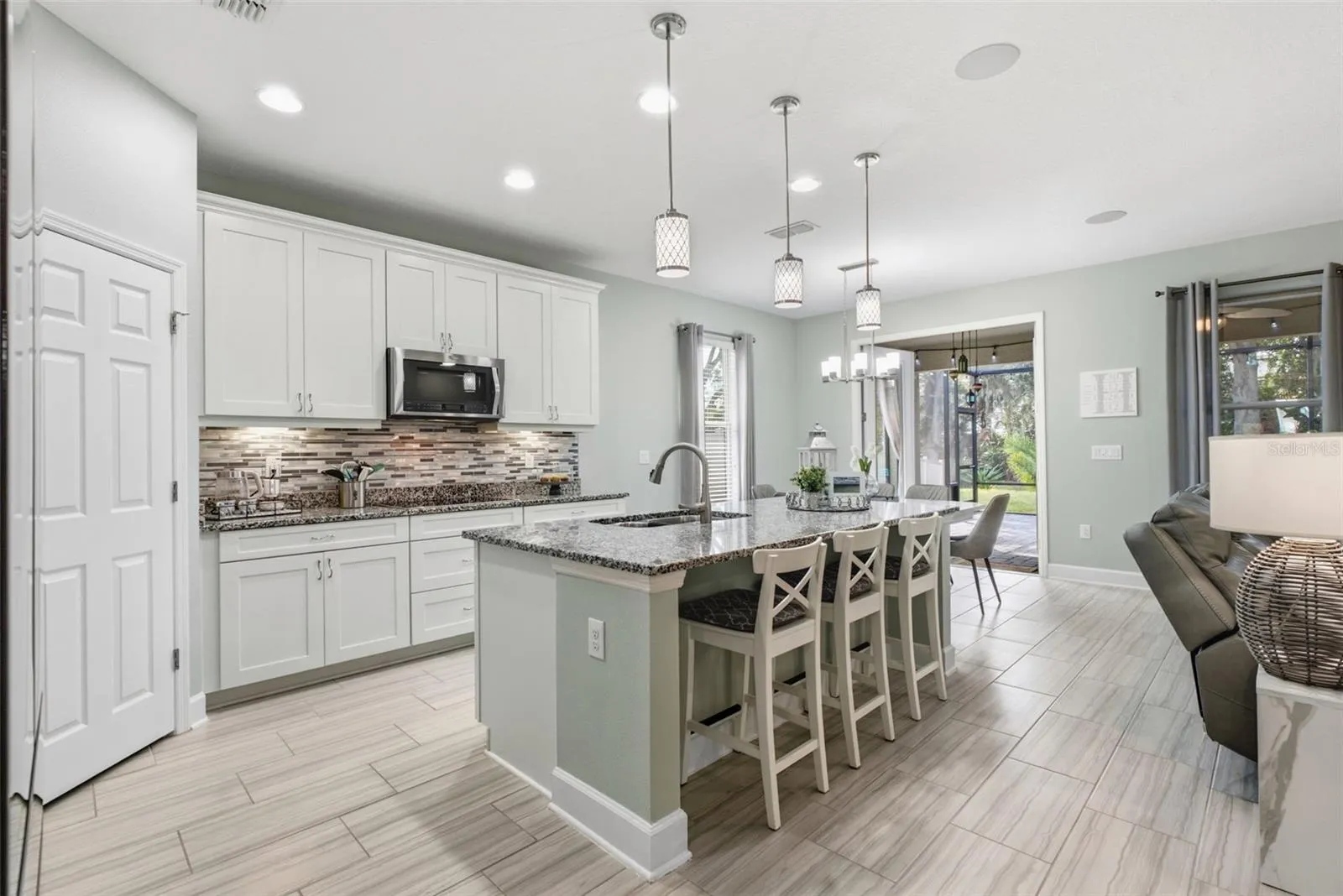 Living room and kitchen flow together, with French doors open to the lanai