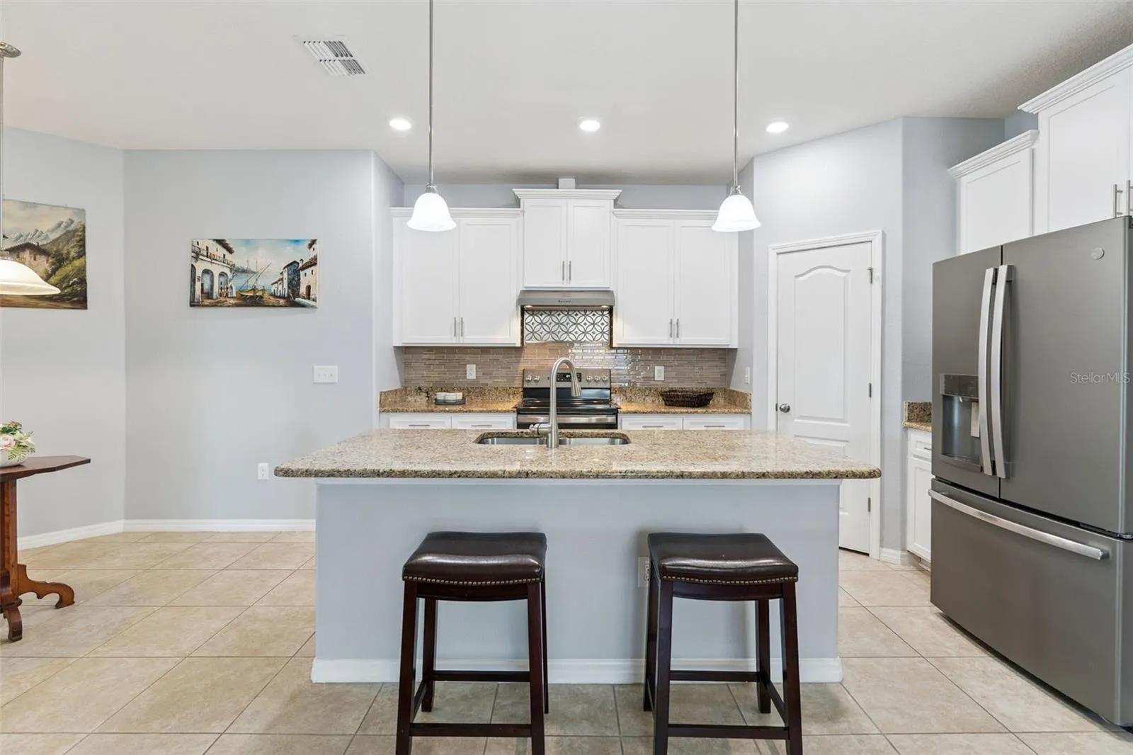 The center island embellished with granite countertops and pendant lighting