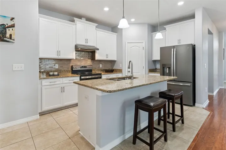 The well-equipped kitchen is a chef’s delight, with fingerprint-resistant stainless-steel appliance package, recessed lighting, and 42-inch white upper cabinetry enhanced with crown molding, soft-close hinges, and brush nickel hardware. A generous walk-in pantry provides additional storage, while the pull-out cabinet organizers keep everyday items conveniently within reach.