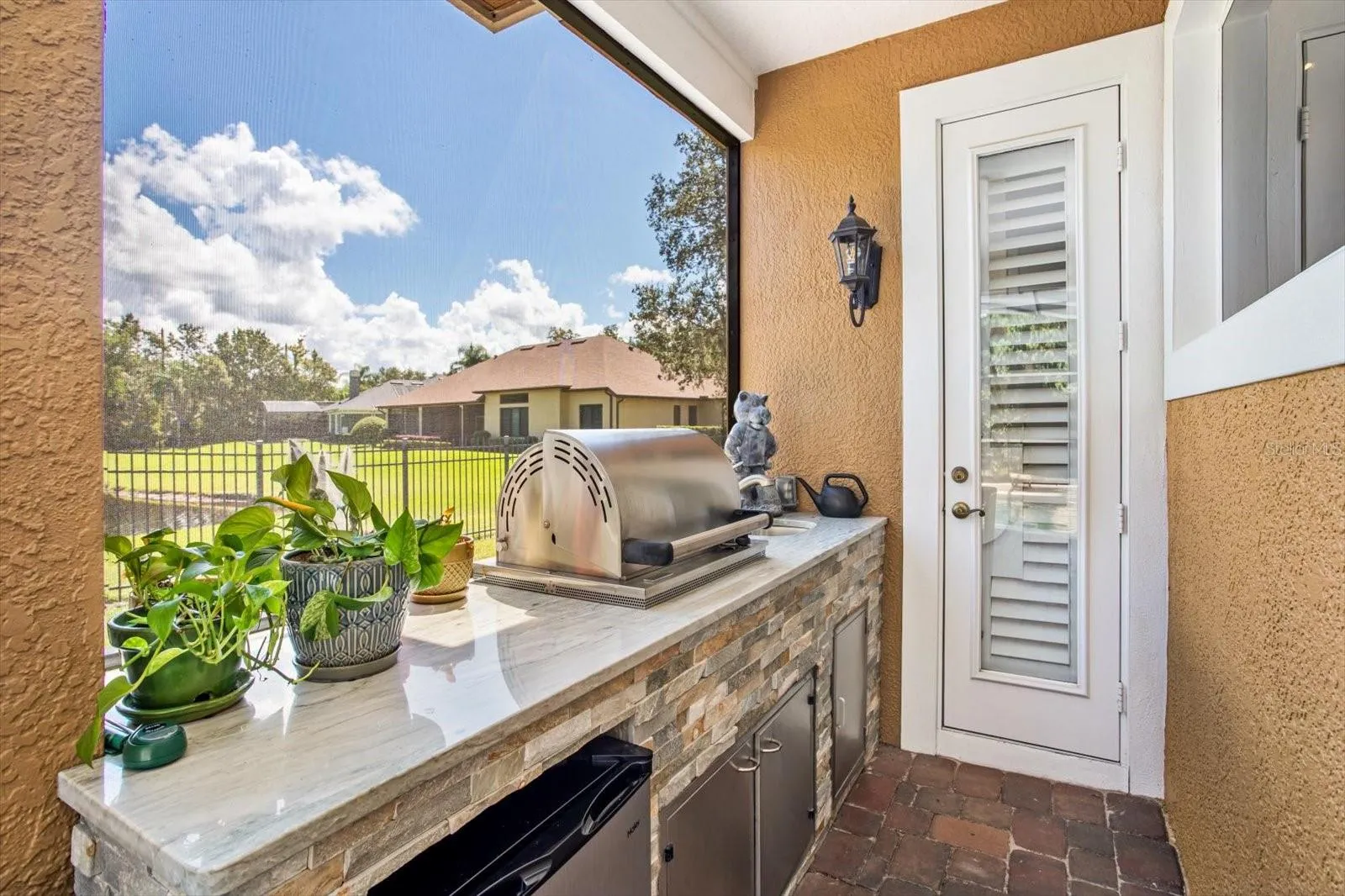 Stacked Stone Summer Kitchen under covered area with built-in propane tank and beverage fridge