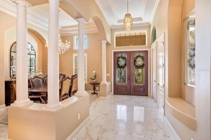 Updated Double-Front Doors with beveled glass inset and transom windows. Extended and wide foyer showcases the marble flooring in the living areas.