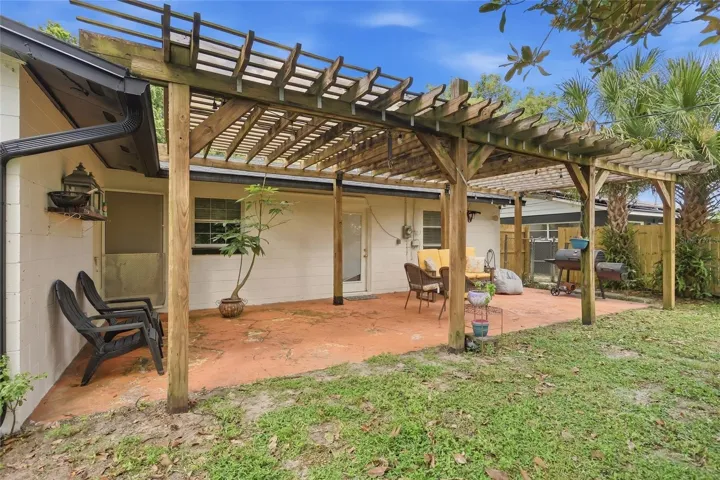 The rear patio extends the gathering space beneath a wood pergola.
