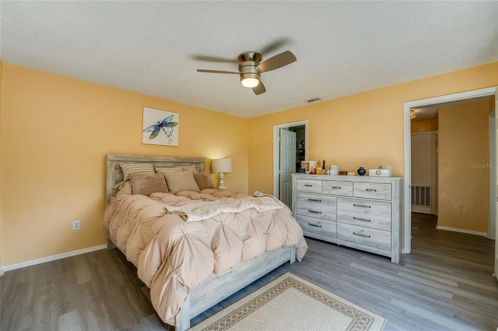 Well-lit room highlights modern vinyl plank flooring, neutral walls, and a ceiling fan.