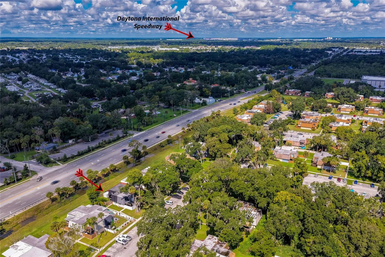 Panoramic aerial perspective highlighting the residence's location relative to surrounding neighborhoods, major roadways, and nearby landmarks like the Daytona International Speedway.