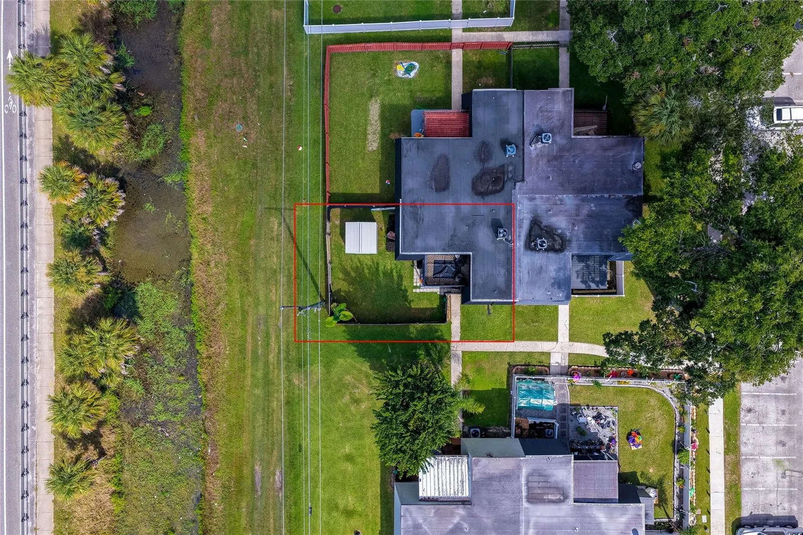 Direct overhead aerial highlighting the property boundaries, unit footprint, and adjacent green buffer zone outlined in red.