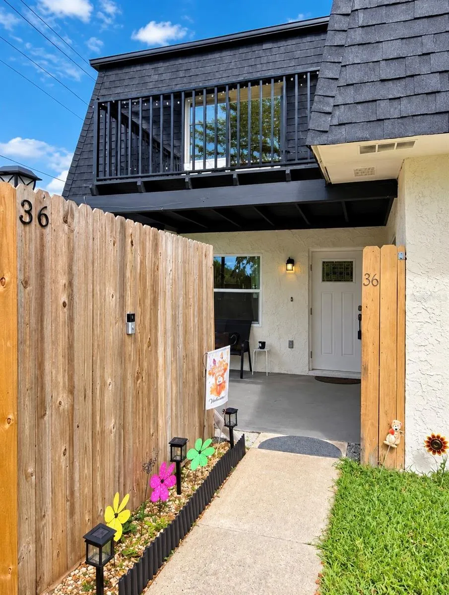 Exterior entry pathway guided by a wooden privacy fence.