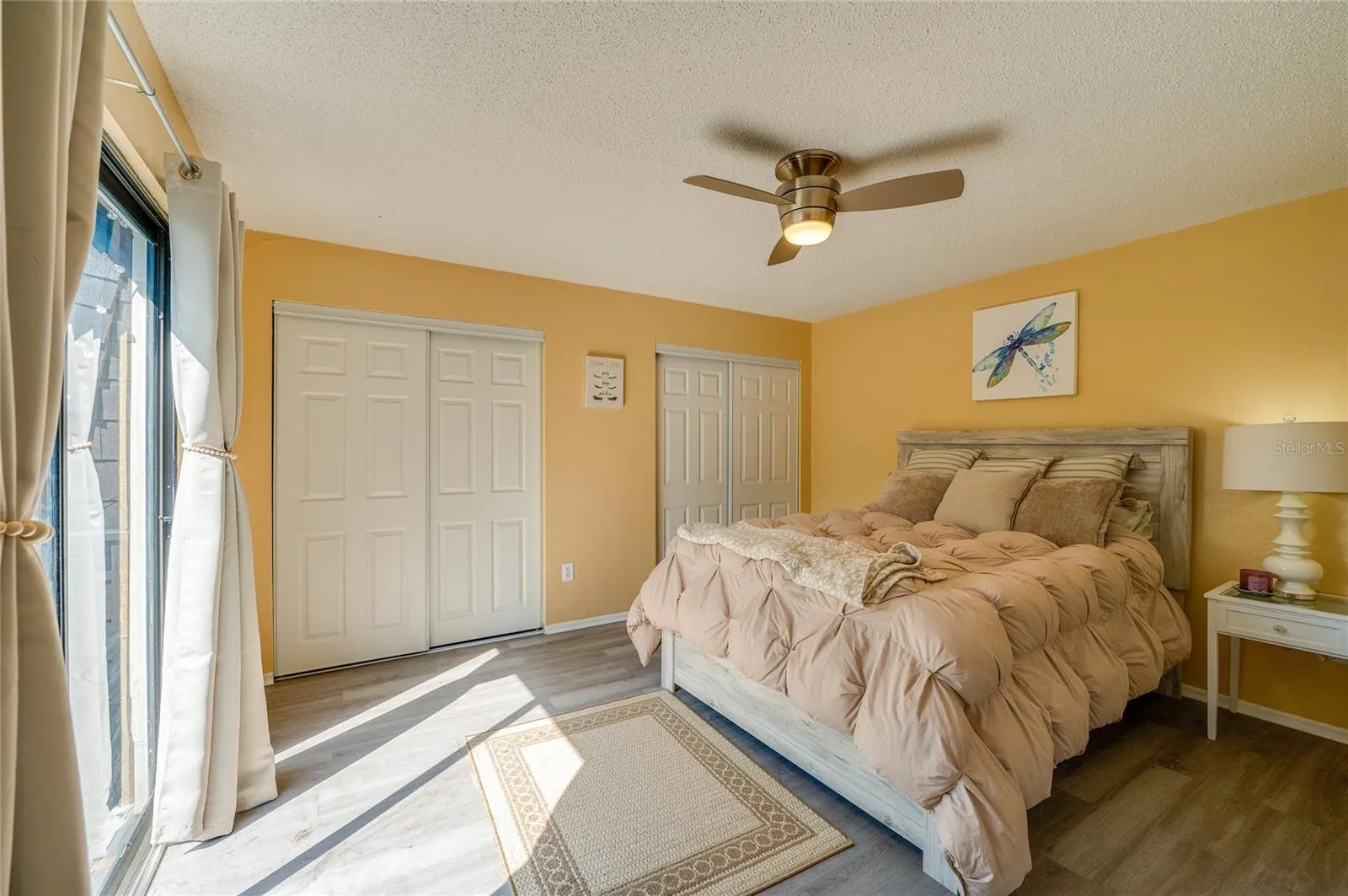 Spacious room showcasing LVP flooring, twin closet spaces with white doors, and direct outdoor access via sliding glass doors.
