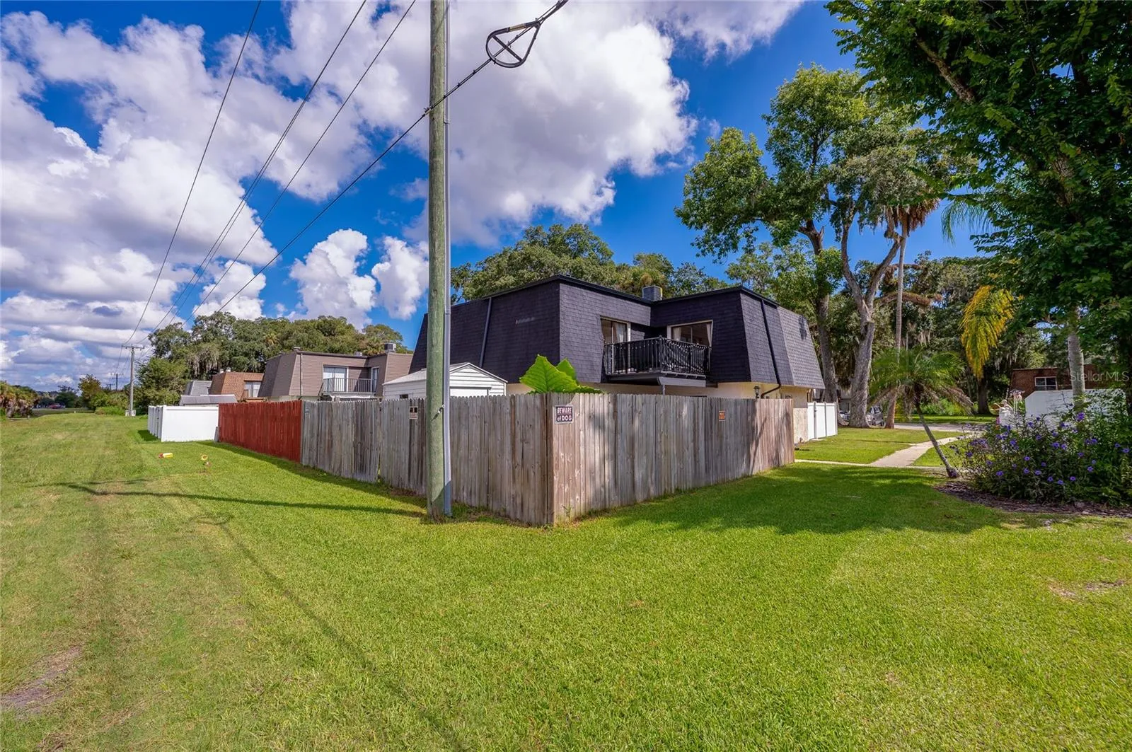 Corner perspective highlighting the fully enclosed yard, roofline, and surrounding green lawn space.