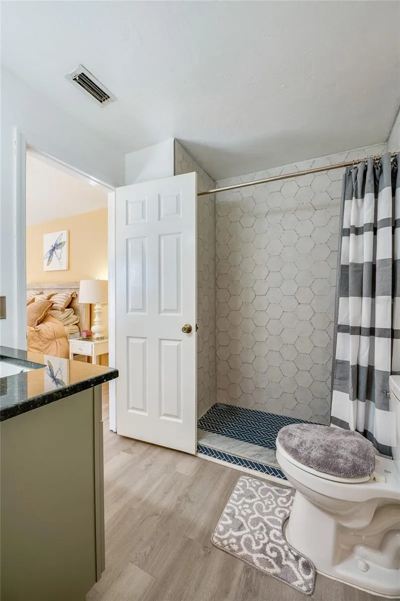 Bathroom interior showcasing a tiled shower enclosure with herringbone floor tile and LVP flooring.