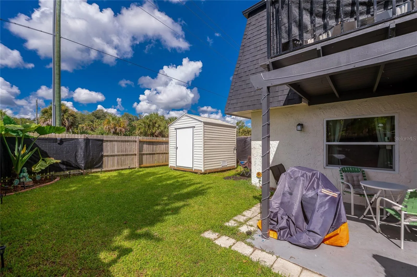 Generously sized yard featuring a detached storage shed, privacy fencing, and a concrete patio area.