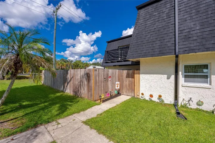 Exterior entry pathway guided by a wooden privacy fence.