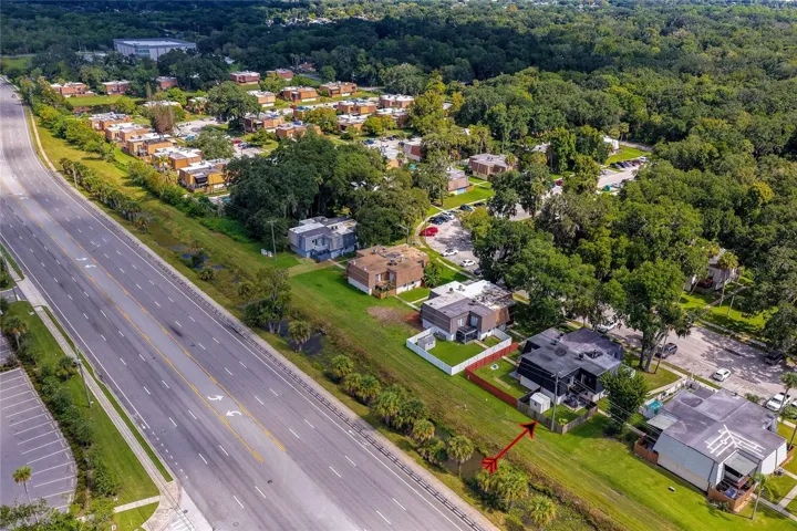 High-altitude aerial capture highlighting the unit's proximity to main roadways, neighboring communities, and dense greenery.