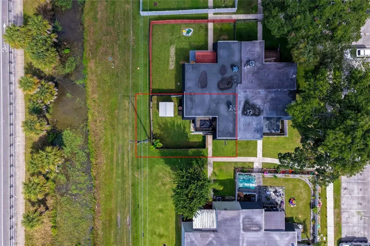 Direct overhead aerial highlighting the property boundaries, unit footprint, and adjacent green buffer zone outlined in red.