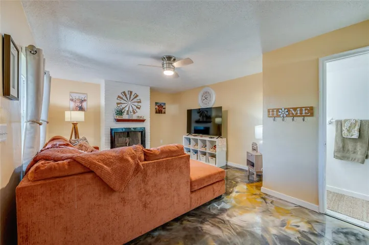 Spacious living area showcasing unique epoxy flooring, warm neutral walls, and a white brick accent wall with a fireplace.