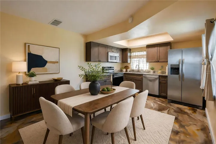 Virtually Staged - Functional kitchen equipped with stainless steel appliances, dark wooden cabinetry, granite countertops, and epoxy flooring.