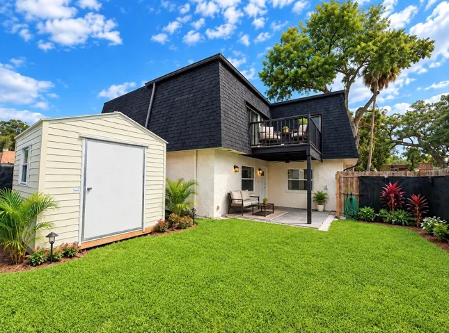 Generously sized yard featuring a detached storage shed, privacy fencing, and a concrete patio area.