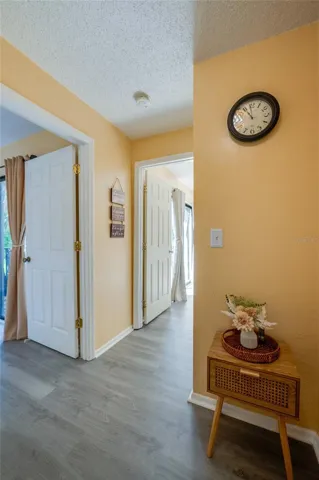Bright, welcoming hallway featuring light wood-look flooring, warm yellow walls, and smooth transitions to adjacent rooms.