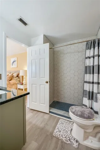 Bathroom interior showcasing a tiled shower enclosure with herringbone floor tile and LVP flooring.