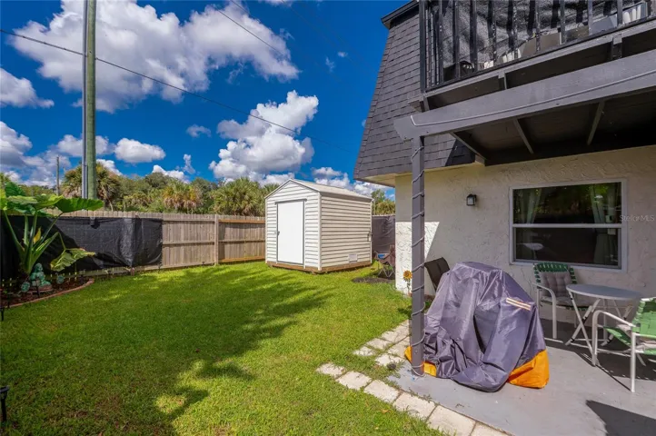 Generously sized yard featuring a detached storage shed, privacy fencing, and a concrete patio area.