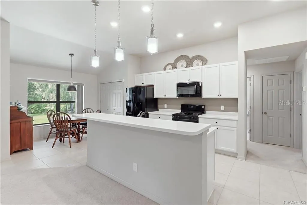 Kitchen w/ Breakfast Nook, White Cabinetry, Quartz Countertops, Black Appliances, Island w/ Raised Breakfast Bar &amp; Pantry Closet