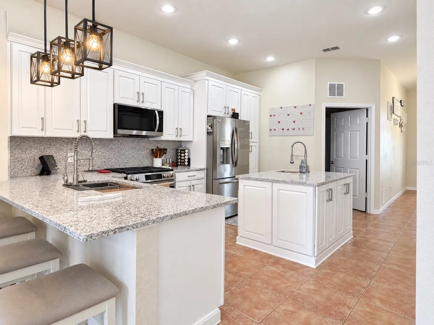 The updated kitchen features new cabinets and countertops, stainless steel appliances, soft-close cabinetry, pull-out storage for pots and pans, pull-out spice storage, Lazy Susan corner storage, additional counter seating, and a center island with prep sink.