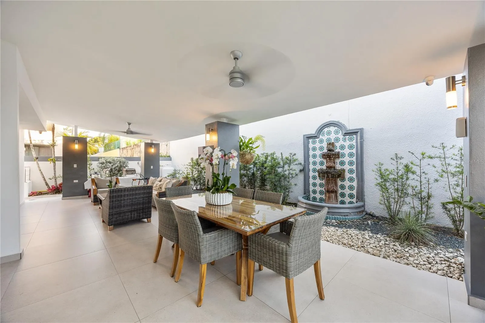 Private covered terrace with ceiling fans, outdoor dining, and a soothing water fountain that fills the space with a peaceful sound