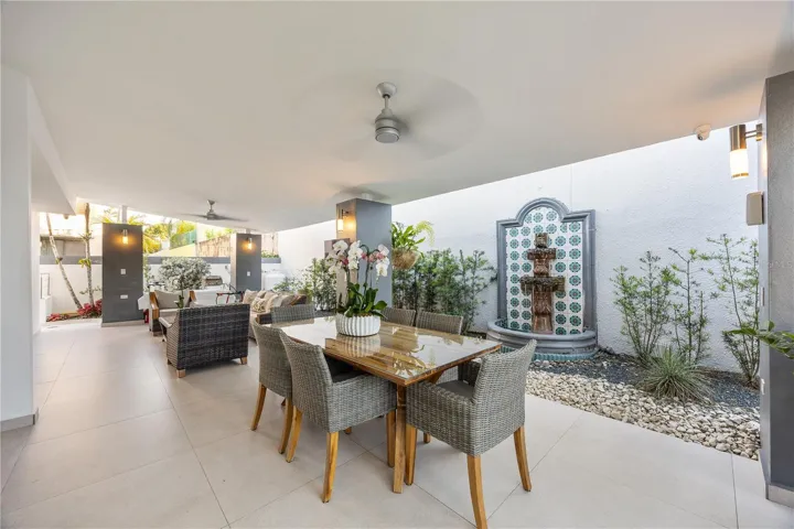 Private covered terrace with ceiling fans, outdoor dining, and a soothing water fountain that fills the space with a peaceful sound
