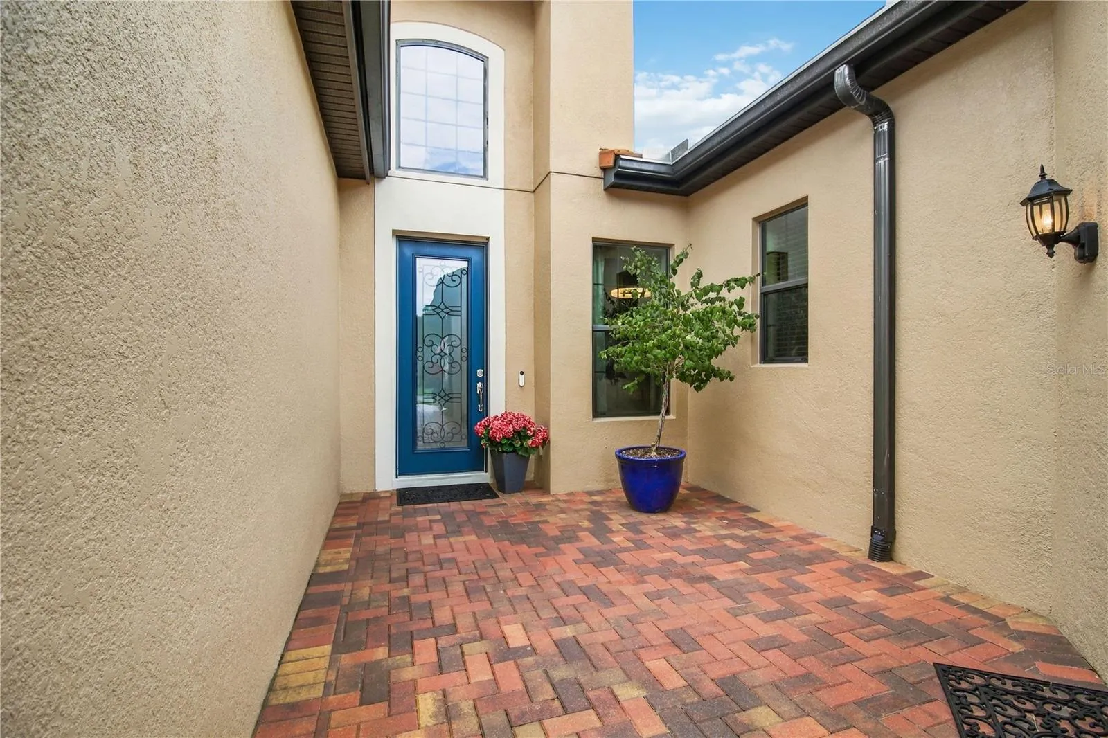 Covered entry porch with blue door and potted plants