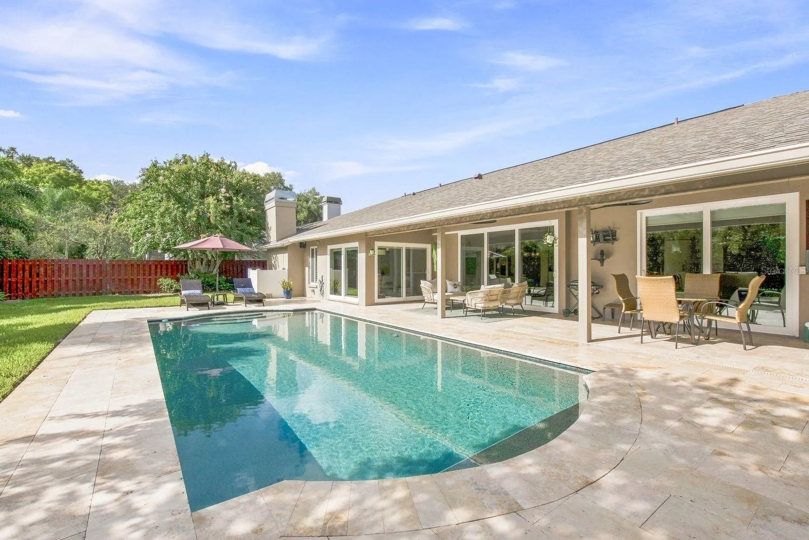 Sleek pebble tech pool with travertine pavers