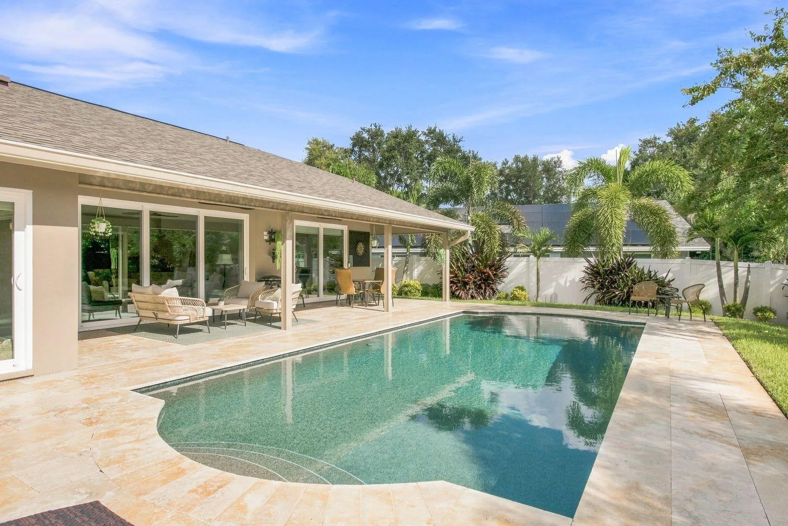 Sleek pebble tech pool with travertine pavers