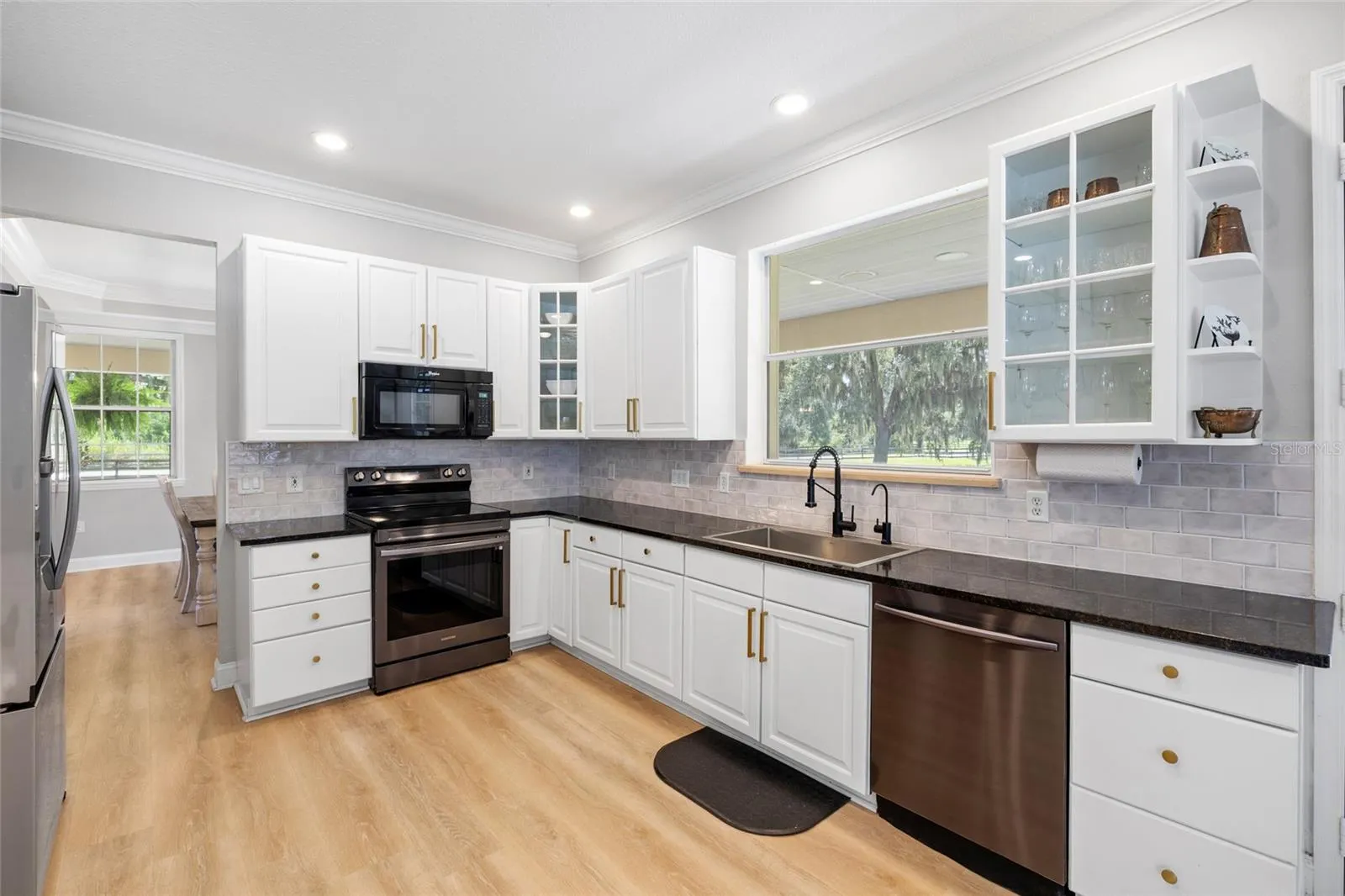 Kitchen open to formal dining area. Window over sink looks out over the pond and firepit.
