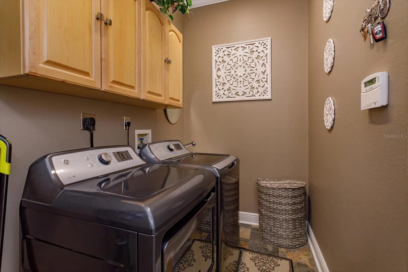 Laundry room has built-in utility sink and overhead cabinets