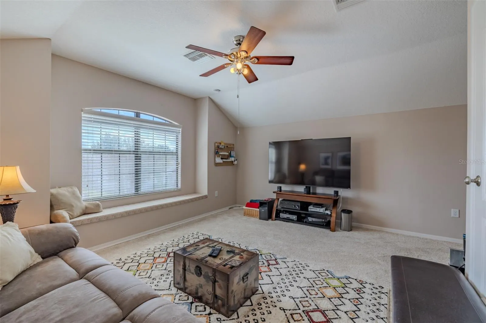 Awesome bonus room with lovely window seat. Bonus room sofa and TV stand convey.