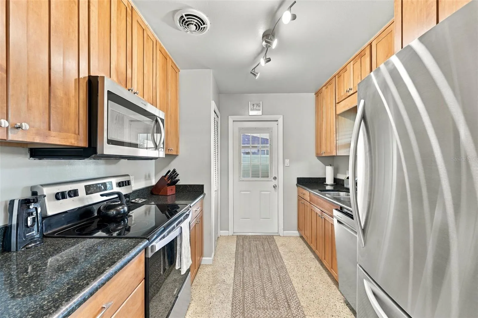 Galley kitchen with all new appliances installed 2024. (Door leads to carport area and utility room.)