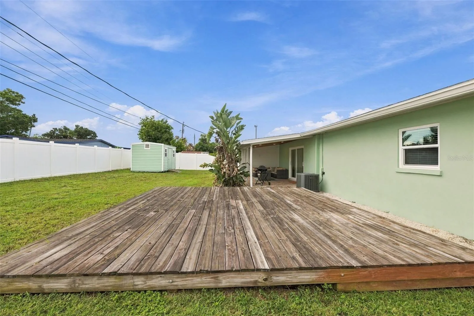 Fenced backyard with shed and deck.