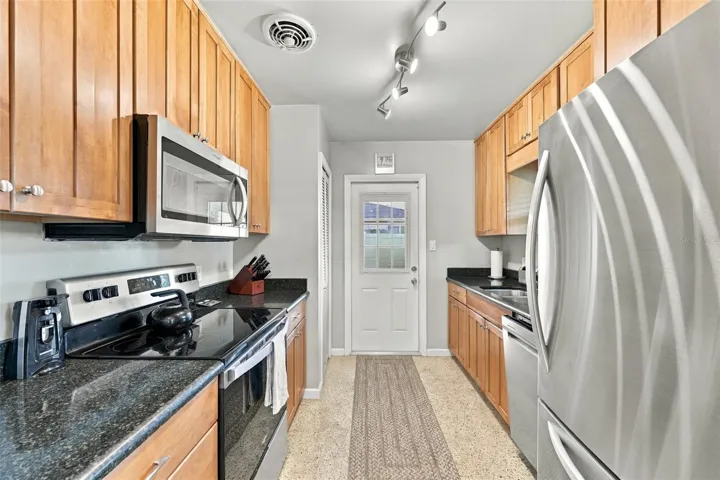 Galley kitchen with all new appliances installed 2024. (Door leads to carport area and utility room.)