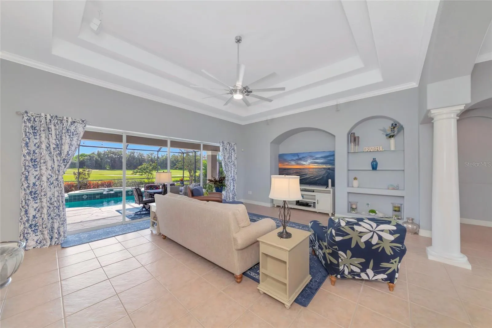 Large great room with double tray ceilings tile floors