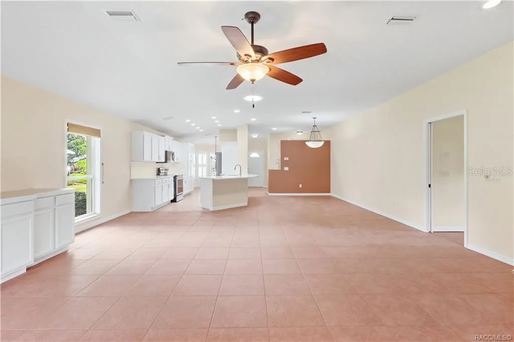 EXPANSIVE FLOOR PLAN – This view really captures the scale of the open living space, with ceiling fan, recessed lighting &amp; uninterrupted sightlines toward the kitchen and front dining area.