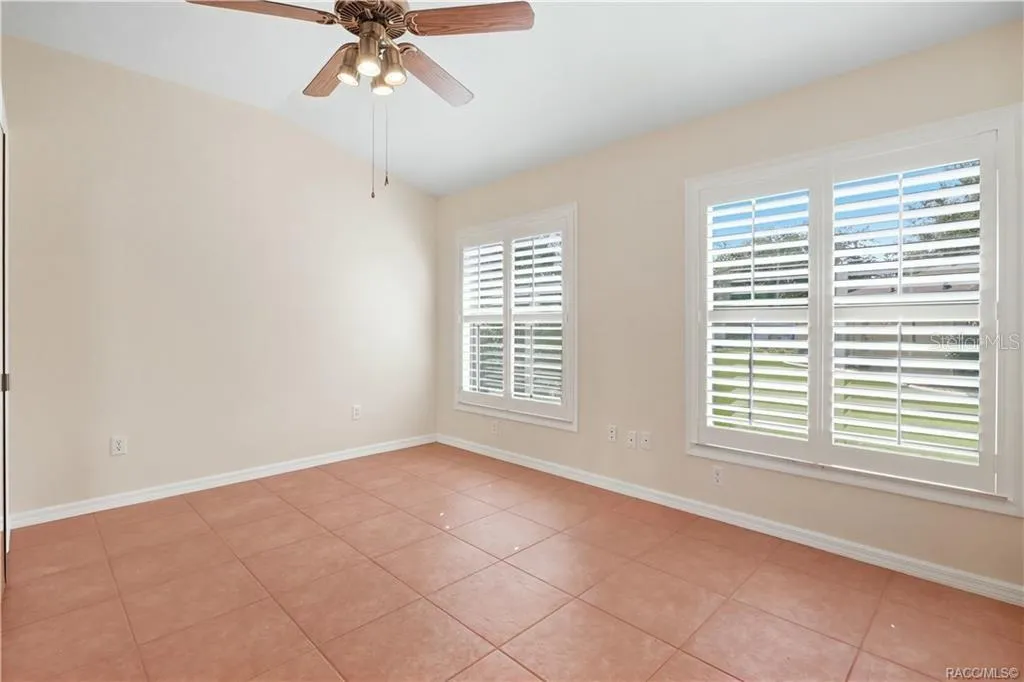 FLEX ROOM / DEN / 4th BEDROOM – Light-filled tiled room featuring ceiling fan &amp; multiple windows with plantation shutters.