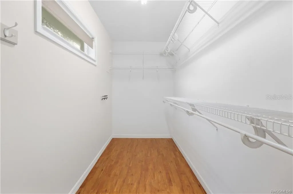PRIMARY WALK-IN CLOSET – Generously sized walk-in closet with extensive wire shelving &amp; hanging space on multiple walls, plus a window for natural light.